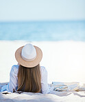 Rearview beautiful young caucasian woman relaxing on the beach. Enjoying a summer vacation or holiday outdoors during summer. Taking time off and getting away from it all. Spending the day alone