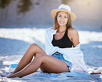 One beautiful young caucasian woman relaxing on the beach. Enjoying a summer vacation or holiday outdoors during summer. Taking time off and getting away from it all. Spending the day alone outside