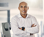 Portrait of one confident mature mixed race call centre telemarketing agent standing with arms crossed while working in a call centre. Happy male manager and supervisor operating helpdesk for customer service and sales support