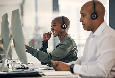 Buy stock photo Happy young african american call centre telemarketing agent talking on a headset while working on a computer in an office alongside a colleague. Confident friendly female consultant operating helpdesk for customer service and sales support