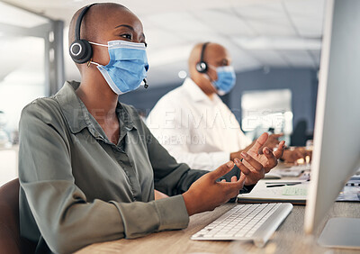Buy stock photo African american call centre telemarketing agent wearing face mask as health and safety protocol talking on headset while using computer in an office. Female consultant operating helpdesk for customer service and sales support during covid pandemic