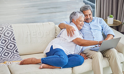 Closeup of an affectionate mixed race senior couple relaxing in their living room at home using a laptop. Hispanic man and wife bonding on the sofa in the living room being affectionate and using a wireless device