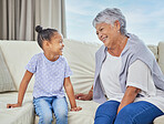 Smiling adorable little mixed race girl hugging her grandmother while bonding with her at home. Beautiful hispanic mature woman showing love and affection to her granddaughter in the living room