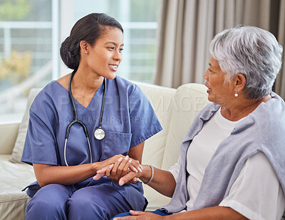 A hispanic senior woman in on a cosy sofa and her female nurse in the old age home. Mixed race young nurse and her patient talking in the lounge
