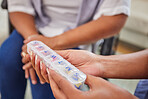 Closeup of a ethnic woman holding her weekly pill box and her nurse helping her