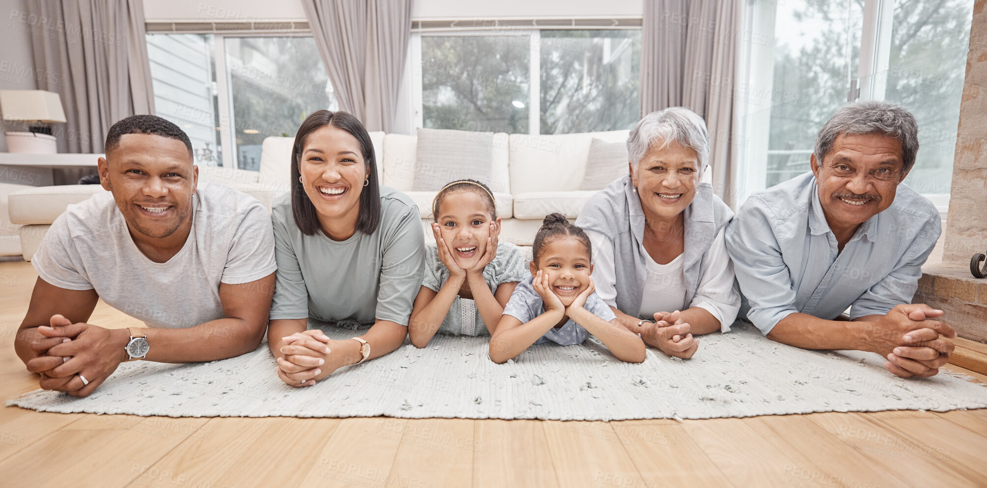 Buy stock photo Happy and affectionate young mixed race family of six lying on the living room floor at home. Married couple with their mother, father and two cute daughters in the lounge. Granny and grandpa visit