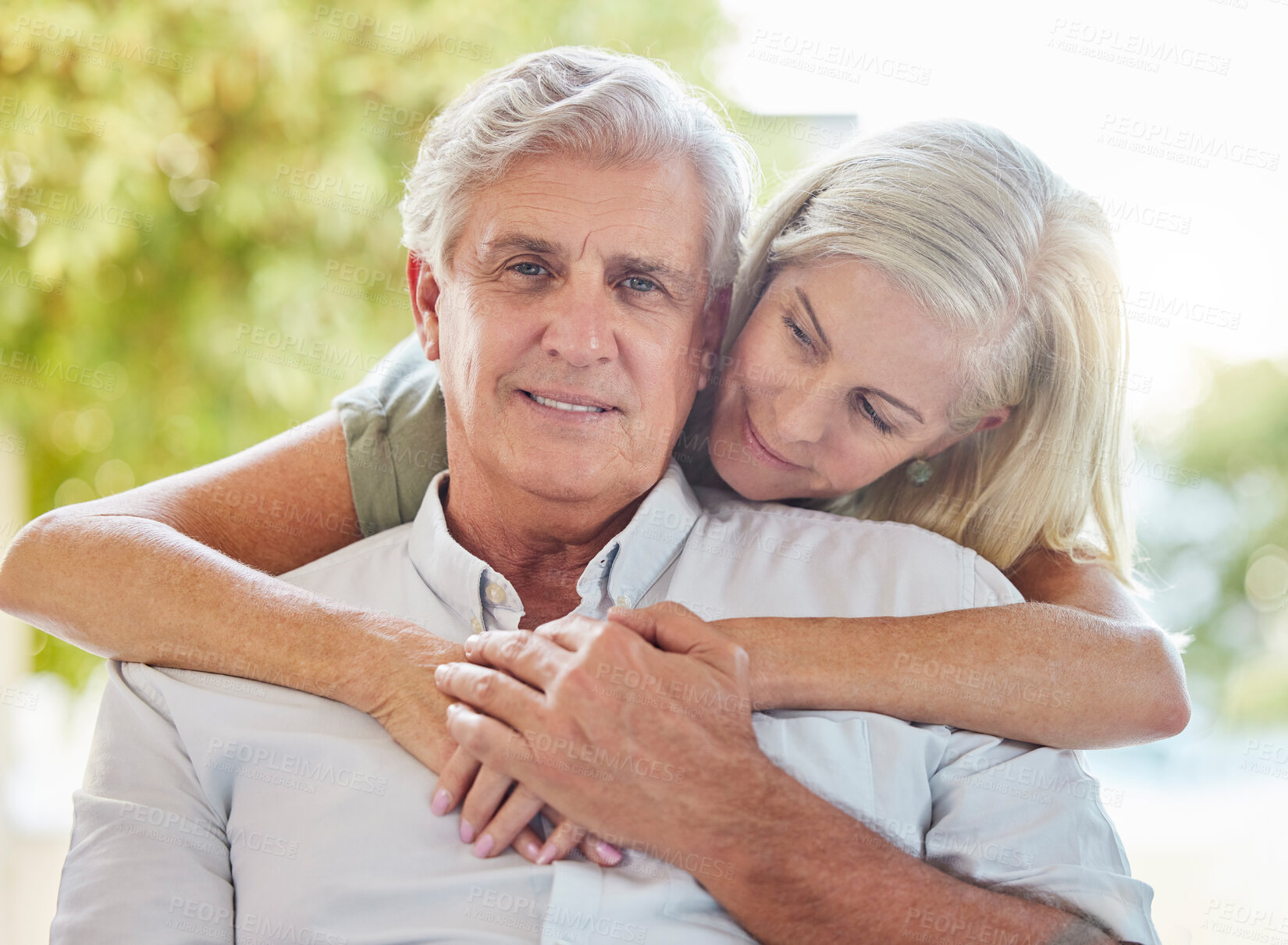 Buy stock photo A happy mature caucasian couple embracing and showing love while relaxing together at home. Retired couple bonding while sitting together
