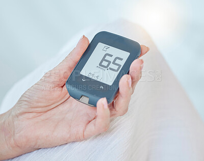 Closeup of a senior diabetic woman checking her blood sugar glucose levels with a diabetes reading strips machine. One unknown elderly woman doing a blood sugar reading at home