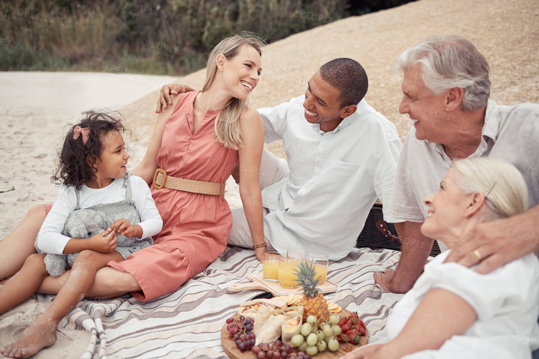 Buy stock photo Interracial couple, girl or family picnic on beach with parents, children or grandparents by sea or ocean in Hawaii. Smile, happy or comic men, women or kids bonding in relax nature reunion with food