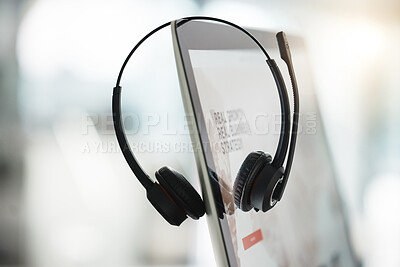 Closeup of headset hanging on a computer desktop monitor in an empty call centre office. Operating helpdesk for customer service and sales support. Telemarketing agents providing online assistance