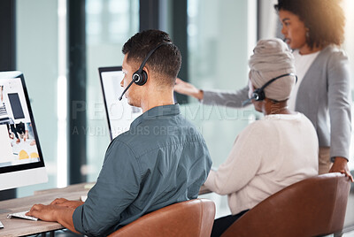 Hispanic call centre telemarketing agent from the back talking on a headset while working on a computer in an office alongside his colleagues. Busy consultants operating a helpdesk for customer service and sales support