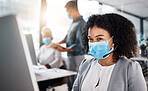 Mixed race call centre telemarketing agent wearing face mask as safety protocol and talking on a headset while using computer in an office. Female consultant operating helpdesk for customer service and sales support during covid pandemic