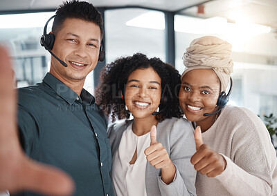 Portrait of a diverse group of happy smiling call centre telemarketing agents gesturing thumbs up while taking selfies together in an office. Confident and ambitious colleagues determined to provide the best customer service and sales support