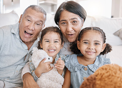 Buy stock photo Closeup of to mixed race grandparents playing with their granddaughters and their teddy bears on the sofa at home. Family having a fun time at home