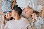 Closeup of a hispanic family laying on the floor at home. Mixed race parents kissing their two daughters while laying on the. floor in the lounge