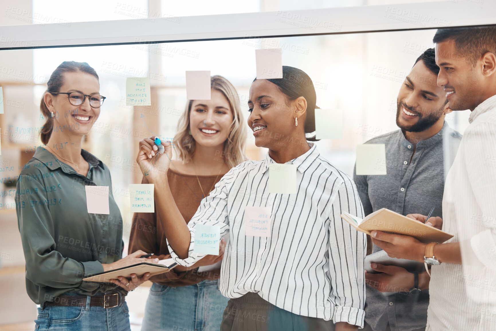 Buy stock photo Meeting, coaching and a business woman writing on glass with her team for strategy or brainstorming in an office. Collaboration, planning and leadership with a female employee teaching her colleagues