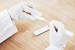 Above closeup woman doctor wearing gloves and using a sterile swab stick while sitting at her desk in the hospital. Testing for the corona virus pandemic. Stop the spread of covid 19 and get tested