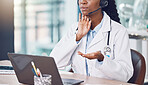 Closeup african american woman doctor using her laptop to do an online remote consult while sitting in her office in the hospital. Testing during the pandemic outbreak. Stop the spread of covid 19