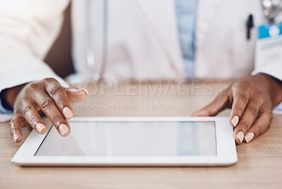 Above closeup african american woman doctor using a digital tablet while working at a desk in her hospital office. Using wireless technology to diagnose diseases in the field of health and medicine
