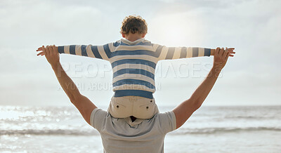 Buy stock photo Cute little caucasian boy from behind cheering with arms outstretched while sitting on his father's shoulders at the beach. Playful young child from the back having fun and bonding with dad outdoors. The innocence of childhood