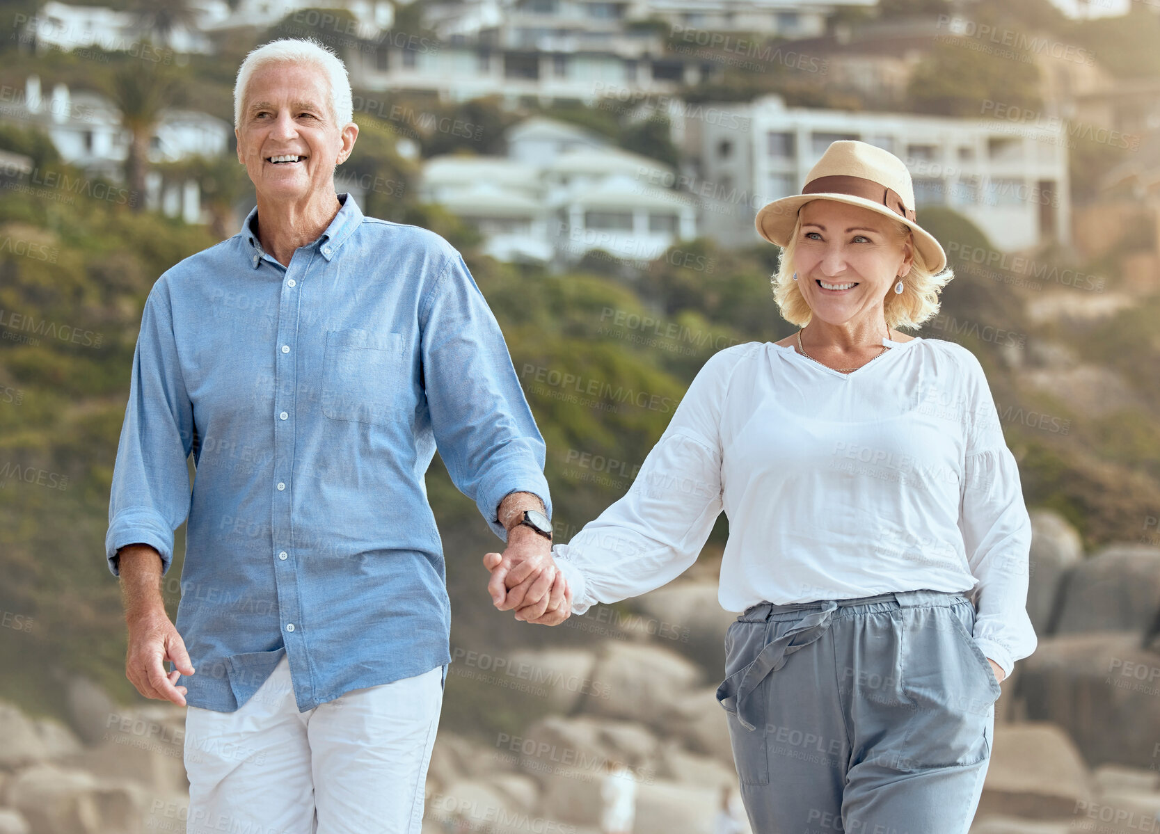 Buy stock photo Happy and loving senior caucasian couple enjoying a romantic walk at the beach together on a sunny day. Cheerful affectionate husband and wife holding hands while bonding on vacation and retirement outdoors