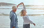 A happy mature caucasian couple enjoying fresh air on vacation at the beach. Smiling retired couple dancing outside