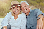 A happy mature caucasian couple enjoying fresh air on vacation at the beach. Smiling retired couple sitting and having a romantic picnic in a garden or backyard