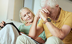 Unhappy elderly couple sitting on a sofa together and looking stressed. Senior caucasian man and woman looking worried about their future while looking at paperwork and their debt