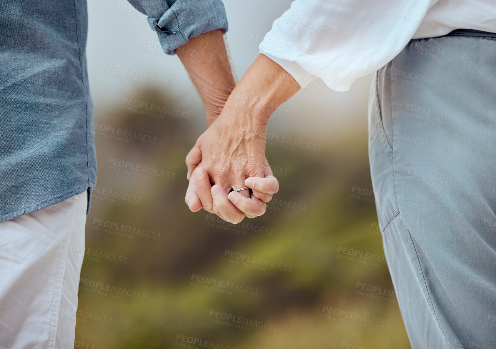 Buy stock photo Closeup of a mature couple holding hands and enjoying a romantic stroll together on vacation at the beach. Older couple holding hands outside