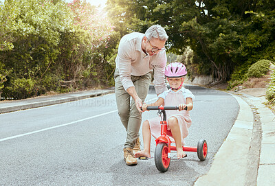 Buy stock photo A happy father teaching his little girl to ride a bike outside. Cute Caucasian child wearing a pink helmet and cycling while bonding with her dad