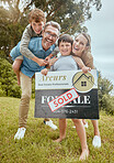 Portrait of happy caucasian family holding a sold sign while relocating and moving into a new house. Smiling parents and kids secure homeowner loan for property real estate and home purchase
