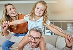 A happy smiling family of three relaxing in the lounge and being playful together. Loving caucasian family bonding with their daughter while playing fun games on the sofa at home