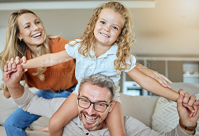 Buy stock photo A happy smiling family of three relaxing in the lounge and being playful together. Loving caucasian family bonding with their daughter while playing fun games on the sofa at home