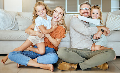 A happy Caucasian family of four relaxing in the living room at home. Loving smiling family being affectionate on the lounge floor. Young couple bonding with their little kids at home