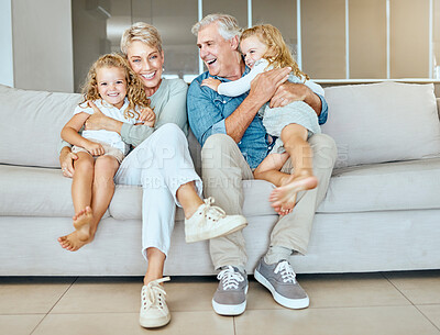 Buy stock photo A happy caucasian mature couple bonding with their foster kids in the living room. Two sisters relaxing with their grandparents on a sofa while they enjoy babysitting two adorable girls