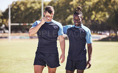 Buy stock photo Two diverse young rugby players standing outside on the field. Black man smiling while talking to his injured and bruised caucasian teammate. Athletic sportsmen discussing and reflecting on the game