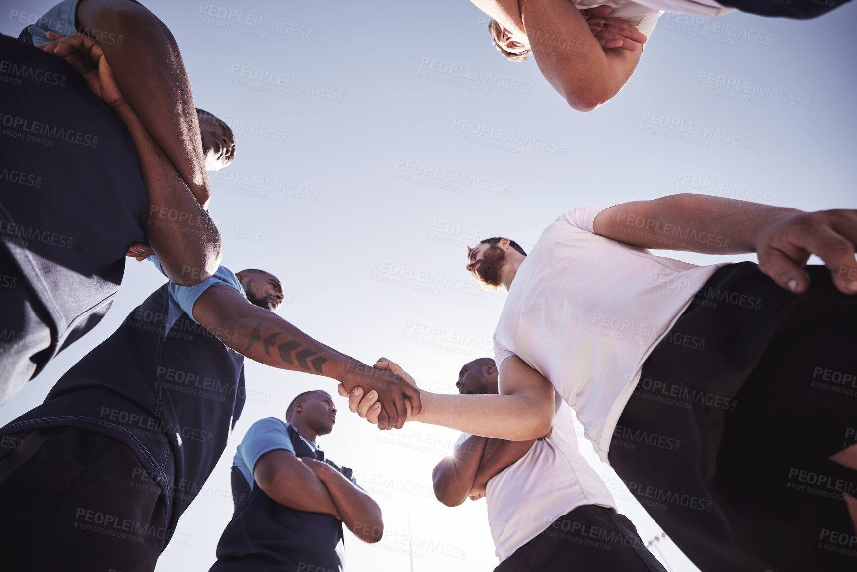 Buy stock photo Below two opponent rugby teams shaking hands before or after a match outside on a field. Rugby players sharing a handshake to show respect and sportsmanship. A mutual understanding of the game