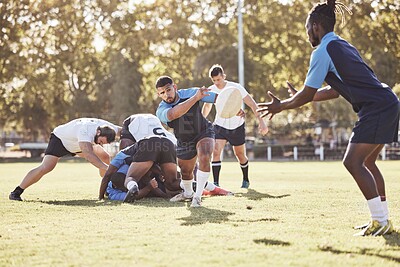 Mixed race rugby player making a pass to an african american teammate during a match outside on a field. Young male athlete passing to his team after winning a contested scrum. Attack on the offensive