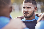Closeup mixed race rugby player standing in a huddle with his teammates outside on a field. Hispanic male athlete looking serious and focused while huddled together with his team. Ready for the game