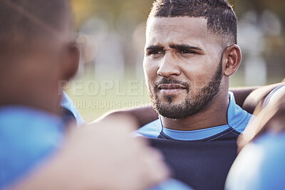 Buy stock photo Closeup mixed race rugby player standing in a huddle with his teammates outside on a field. Hispanic male athlete looking serious and focused while huddled together with his team. Ready for the game
