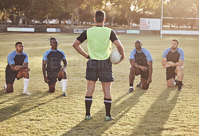 Buy stock photo Rearview rugby coach talking to and addressing his players during a practice session outside on a field. Rugby team listening to their coach while training for the upcoming game. Tactics and gameplan