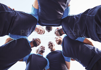 Buy stock photo Below diverse group of rugby players standing in a huddle together outside on a field. Young male athletes looking serious and focused while huddled together as a team. Ready for a tough game