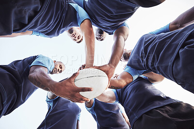 Buy stock photo Below diverse group of rugby players standing in a huddle together outside on a field. Young male athletes looking serious and focused while huddled together as a team. Ready for a tough game