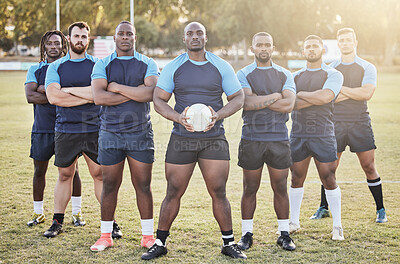 Buy stock photo Portrait diverse young rugby players holding a rugby ball while standing with their arms crossed outside on the field. Men looking confident, ready for a match. Athletic sportsmen focused on the game