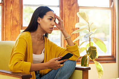 Buy stock photo Stress, tired and woman with headache on phone sitting on chair in the living room of her home. Bad news, burnout and frustrated girl from Colombia scrolling on social media with smartphone in lounge