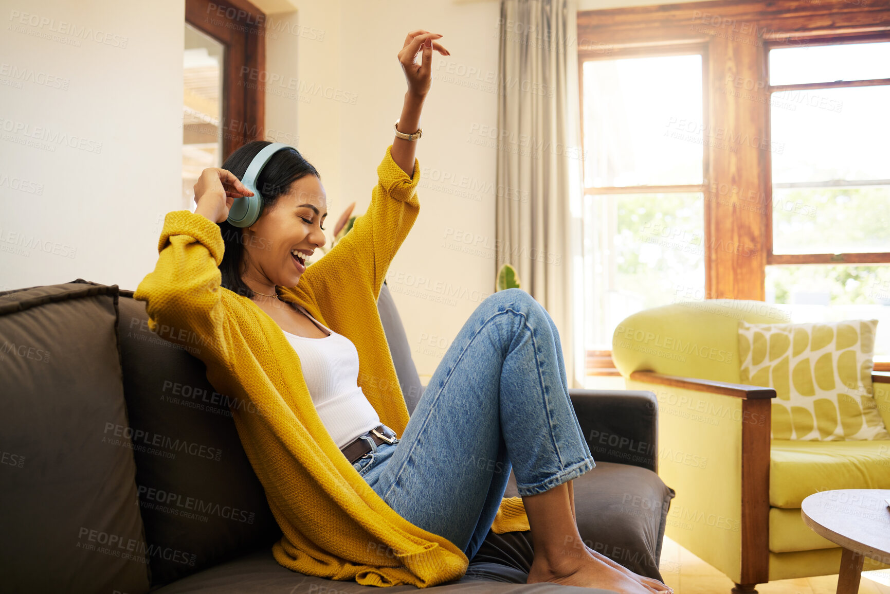 Buy stock photo Woman, music and relax with headphones dancing on living room sofa enjoying good vibes at home. Happy female with smile and dance listening to joyful audio streaming, relaxing on a couch at the house