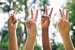 Hands showing the peace sign in the air outside. Diverse group of people gathering for world peace. Closeup of multicultural peoples hands showing the peace sign