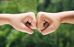 Closeup of a fist bump outside in nature. Two diverse peoples hands greeting. Fist bump in nature