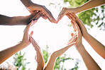 Multiethnic hands making a heart shape outside in nature. Closeup of a group of people making a heart as a concept of togetherness and love. Multicultural young peoples hands together