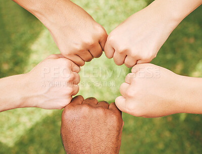 Multiethnic hands fist bumping outside in nature. Closeup of a group of people celebrating by fist bumping. Closed hands in a circle